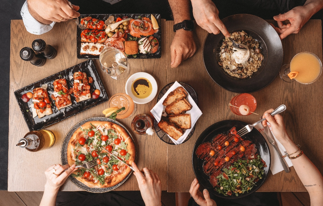 table à manger avec plusieurs plats italiens (risotto, pizza, carpacio...)